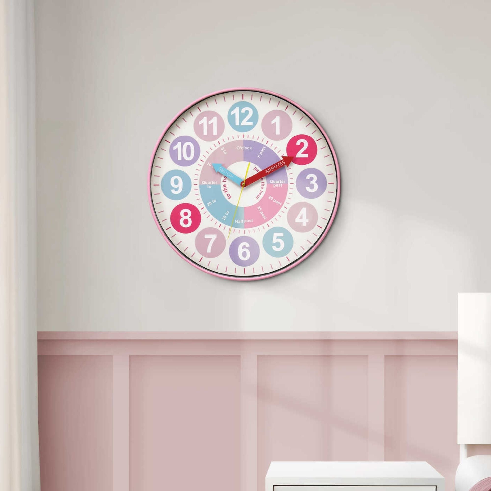 Pink 18-inch diameter wall clock for kids by Monarch Specialties with colorful numbers and playful design.
