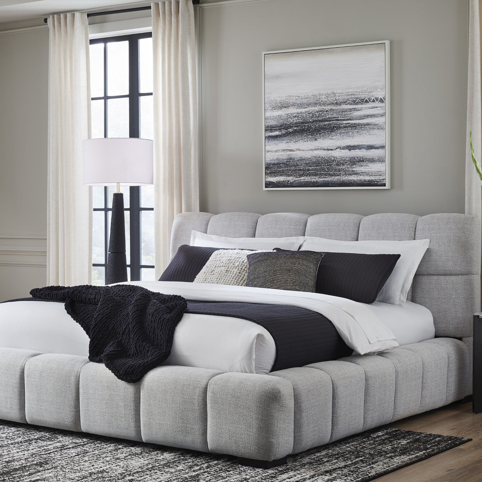 Light gray upholstered Ashley bed by Signature Ashley with a padded headboard and modern design, shown in a bedroom setting.