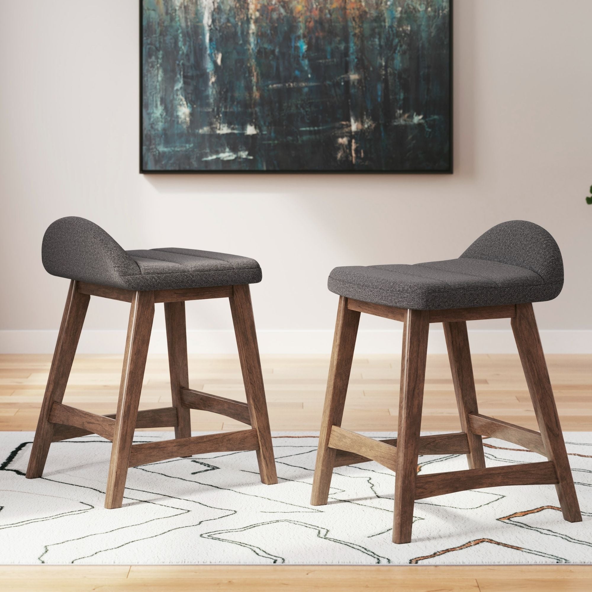 Two charcoal upholstered Signature Ashley barstools with wooden legs and backrests, ideal for modern kitchen or bar area.