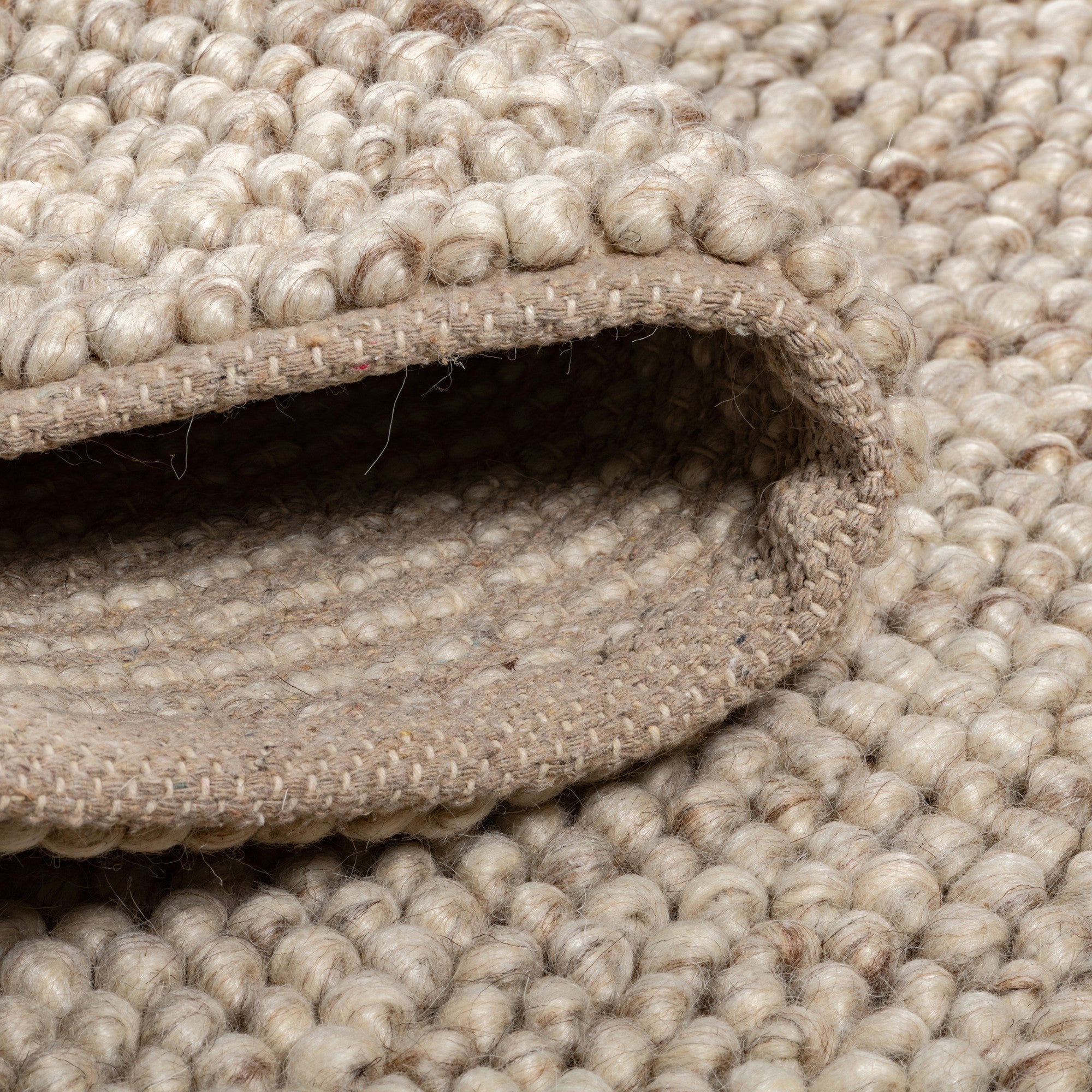 Viana Inc Calabria handmade wool area rug with intricate patterns and warm neutral tones, showcasing craftsmanship and soft texture.