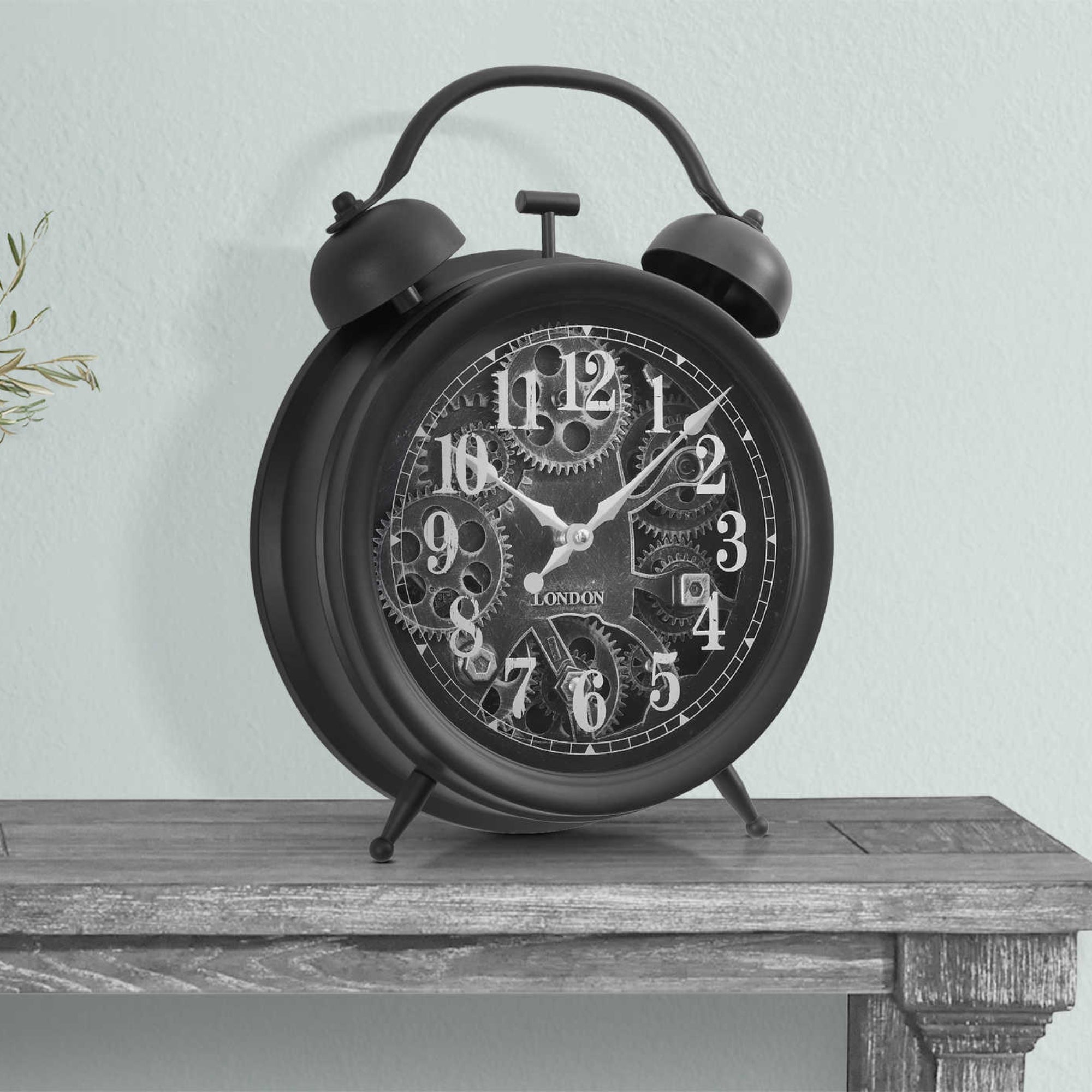 Black table top clock with visible gear mechanism by Monarch Specialties, featuring a modern design and functional clock face.