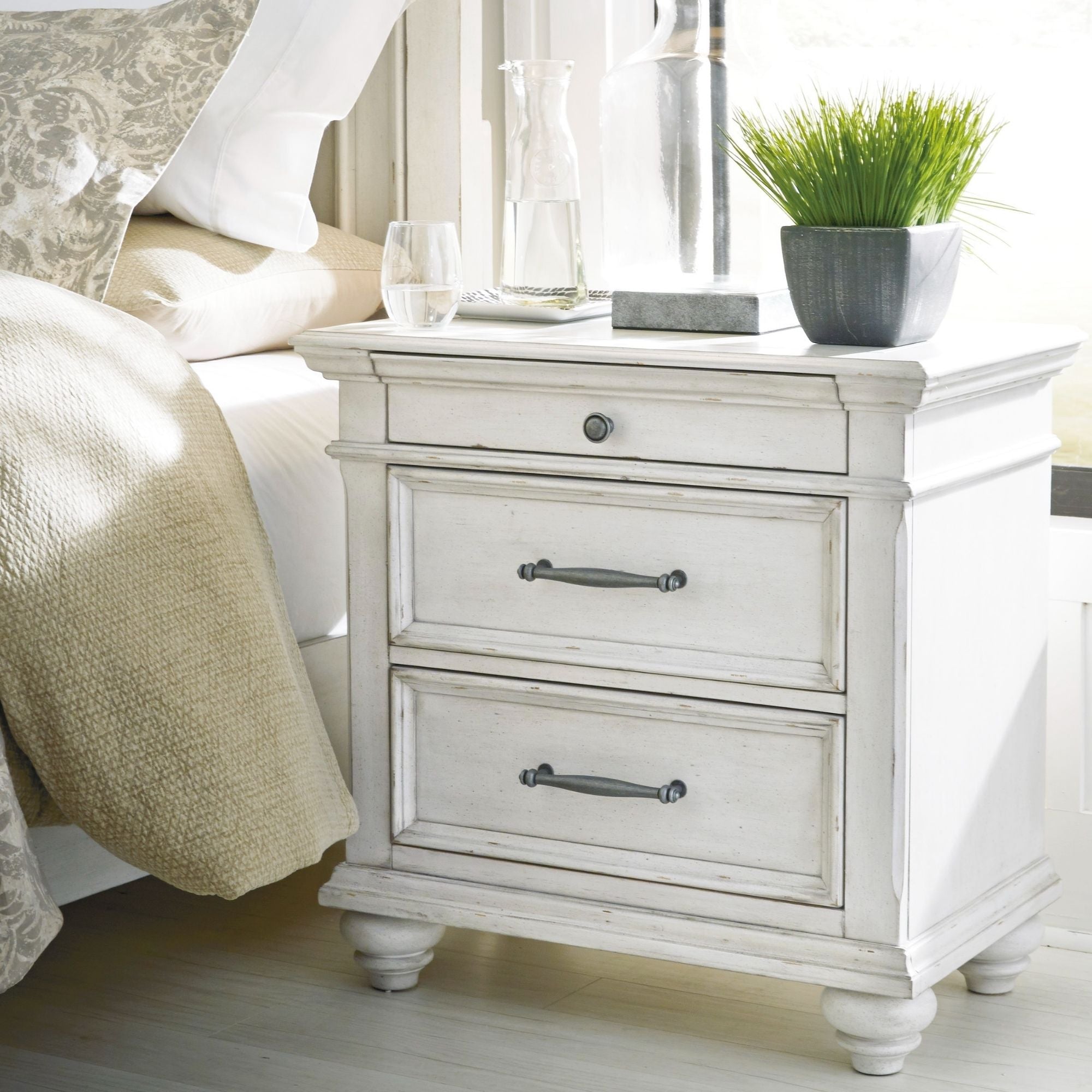 Signature Ashley Kanwyn three-drawer nightstand with wood finish, featuring sleek handles and a modern bedroom furniture design.