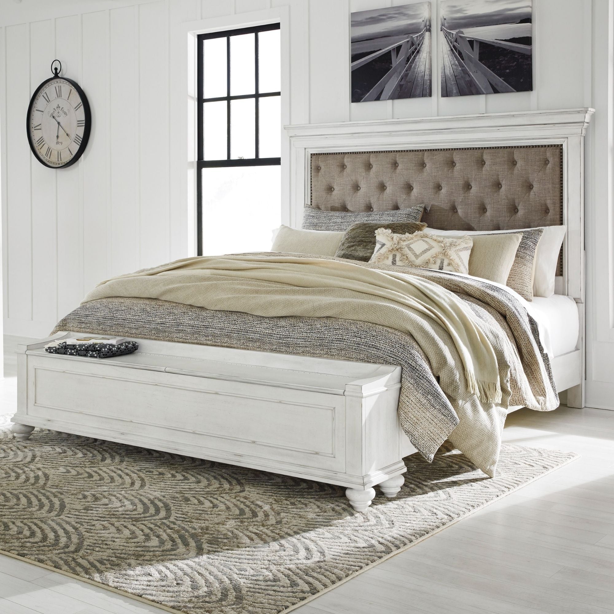 White upholstered Kanwyn panel bed with built-in storage bench from Signature Ashley, shown in a modern bedroom setting.