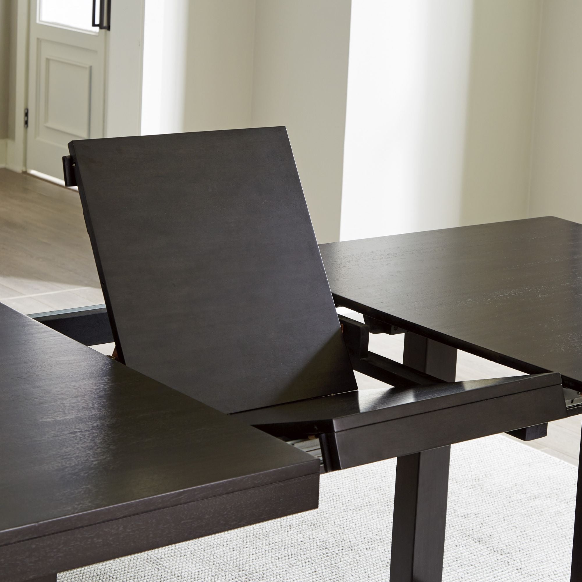 Neymorton dining extension table by Signature Ashley in a modern dining room setting with seating and decorative accents.