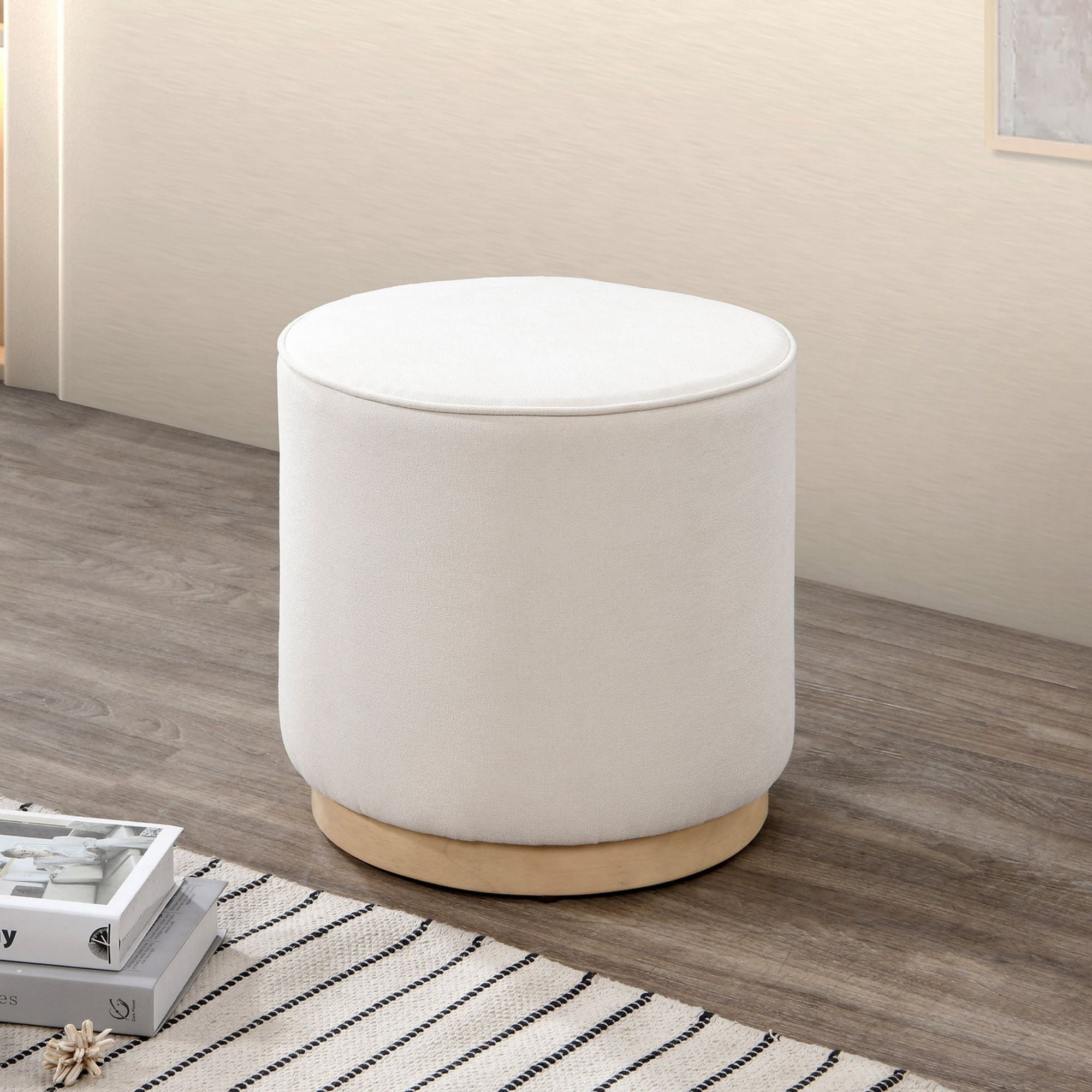 Modern round ottoman with cream fabric from IFF, featuring a sleek design suitable for living rooms or seating areas.