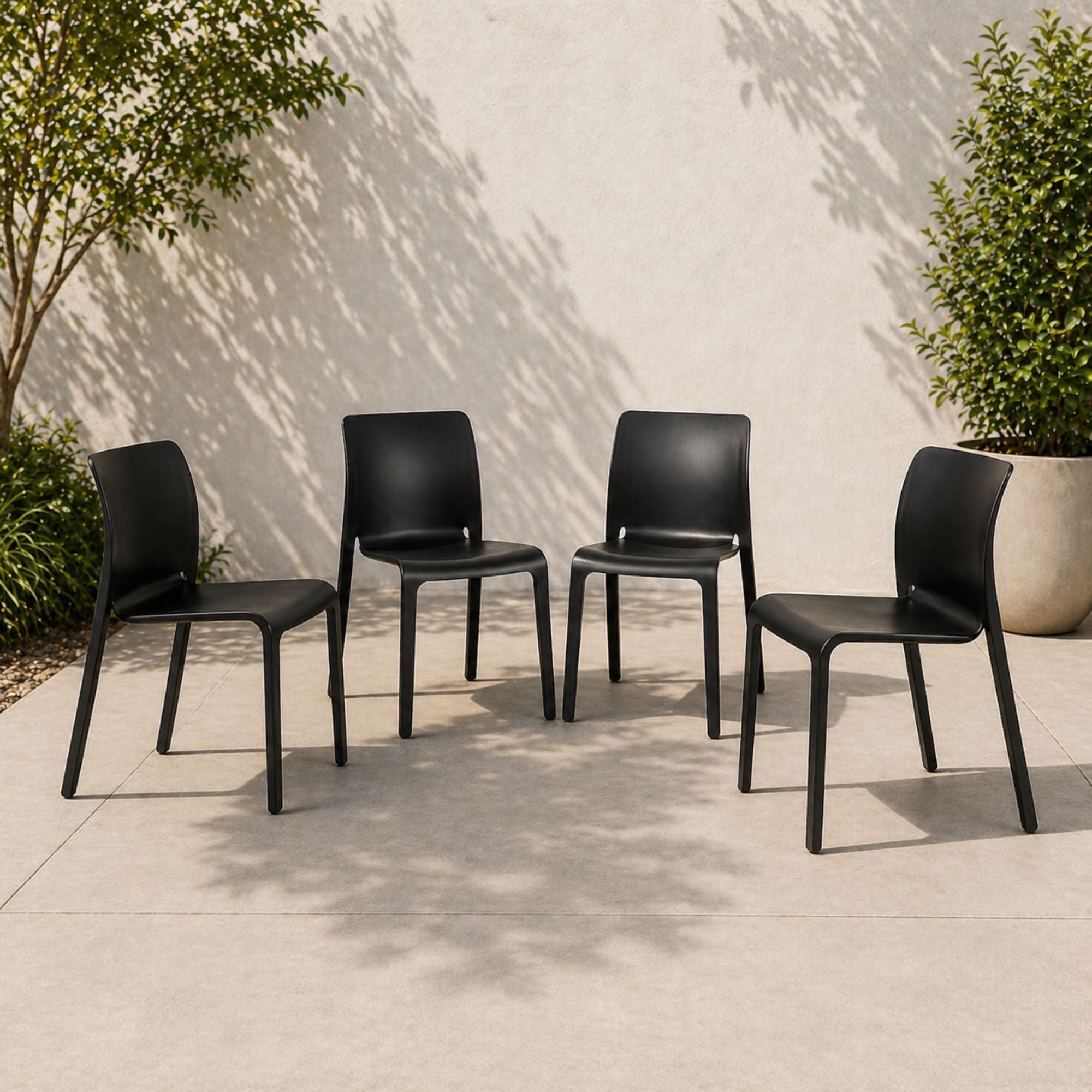 Set of four Elite Living Faro stackable black dining chairs shown outdoors, featuring modern design and sturdy construction.