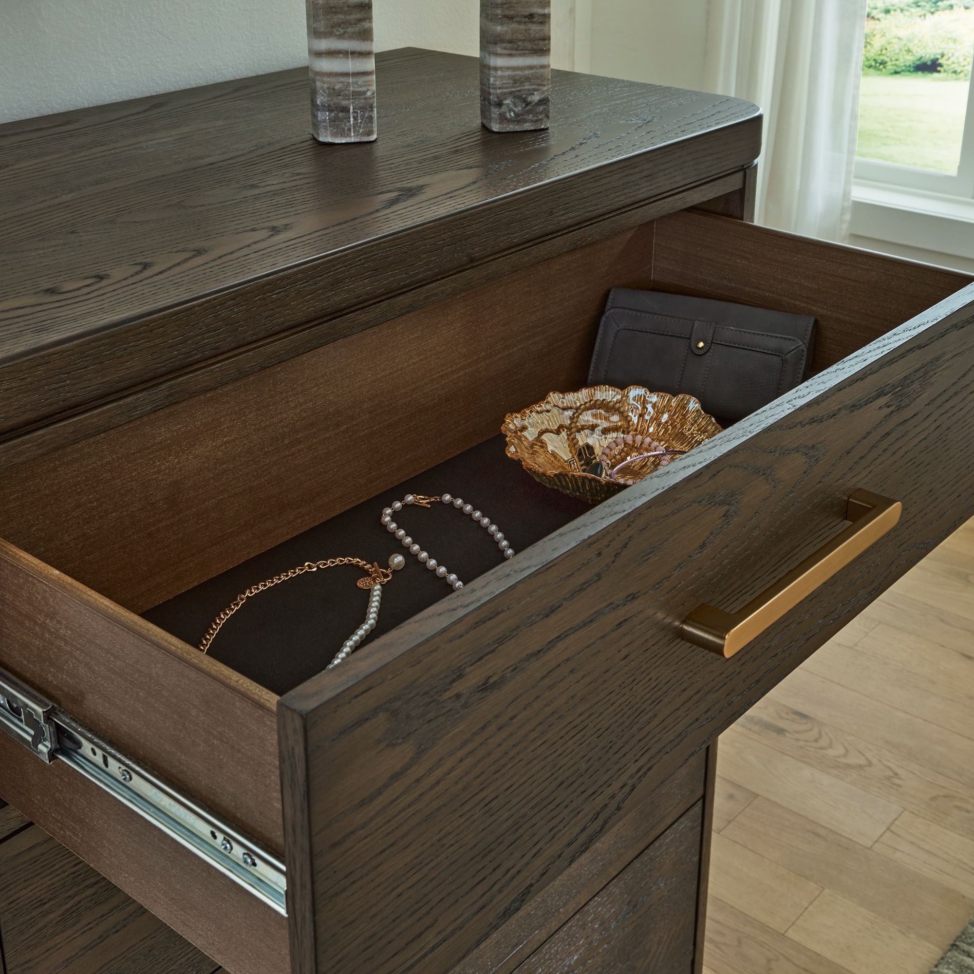 Five-drawer chest from the Radkin bedroom collection by Signature Design by Ashley, featuring dark wood finish and modern hardware.