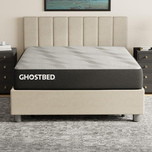 GhostBed Essential 11-inch foam mattress with a neutral-colored fabric cover, shown on a bed frame in a bedroom setting.