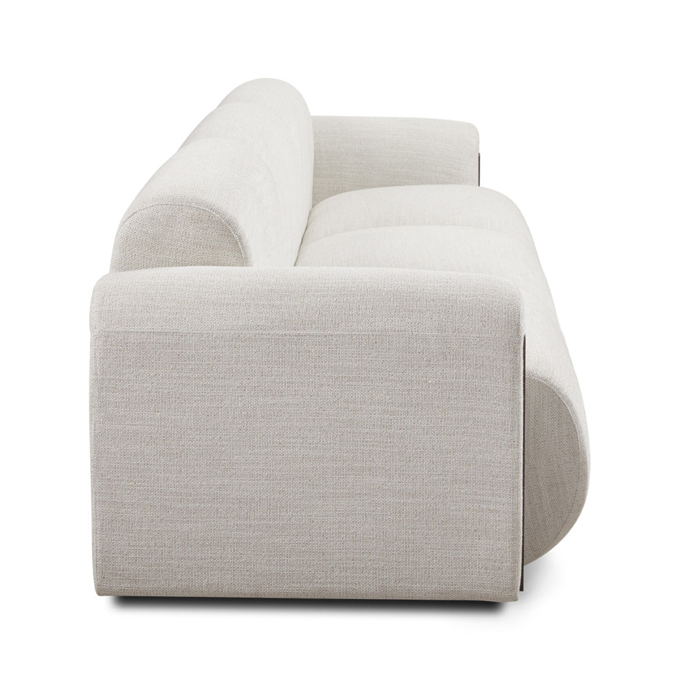 Xcella Designers Collection Brenton 4-seater sofa with plush cushions and sleek fabric upholstery, shown from a side angle.